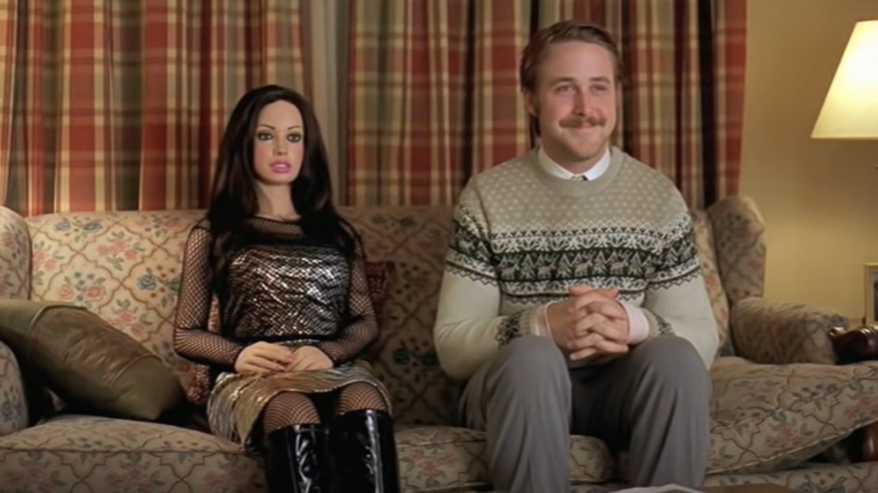 A sex doll and Ryan Gosling as Lars sitting next to each other on a couch in Lars and the Real Girl.