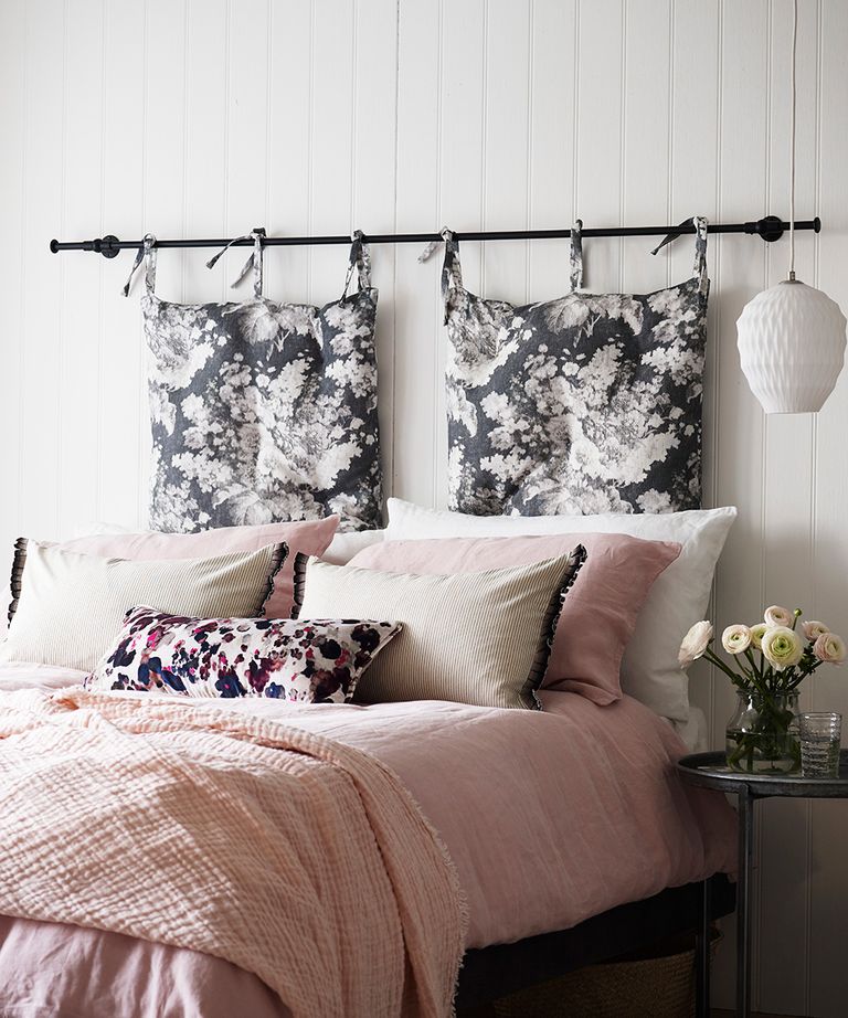 卧室天花板灯创意的一个例子，展示了一张带靠垫的粉色床和一个白色吊灯旁边的粉色吊坠