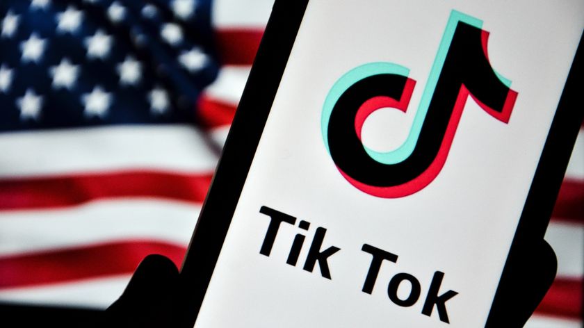 A phone displaying the TikTok logo in front of the US flag.