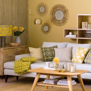 yellow living room with grey chaise sofa, yellow cushions, throw, and lamp, with gold mirrors and floor lamp