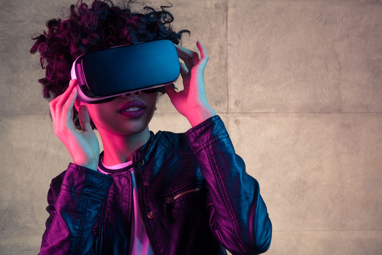 Pretty young African girl adjusting the VR headset on the white background