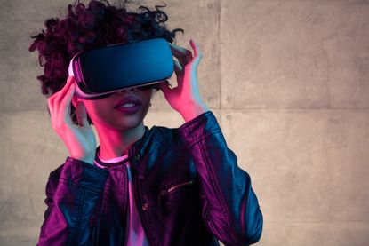 Pretty young African girl adjusting the VR headset on the white background
