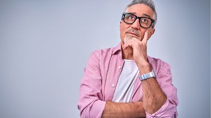 An older man looks into the distance with a thoughtful expression on his face.