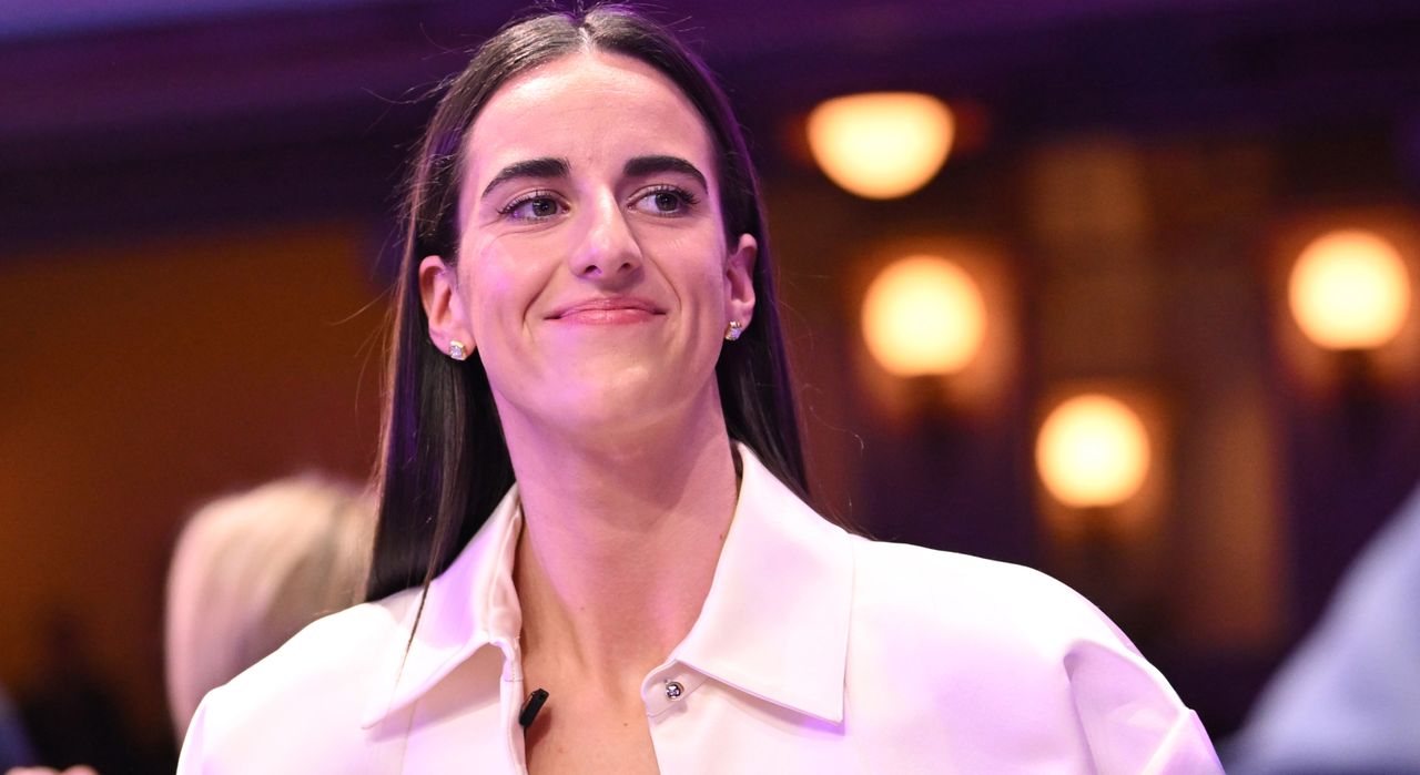 Caitlin Clark attends the WNBA draft for 2024 wearing Glossier beauty and a full Prada outfit