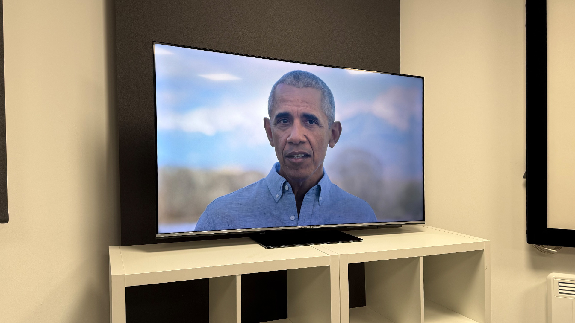 Mitchell &amp;amp; Brown QLED1811 QLED TV on white shelving unit, on screen is Barack Obama