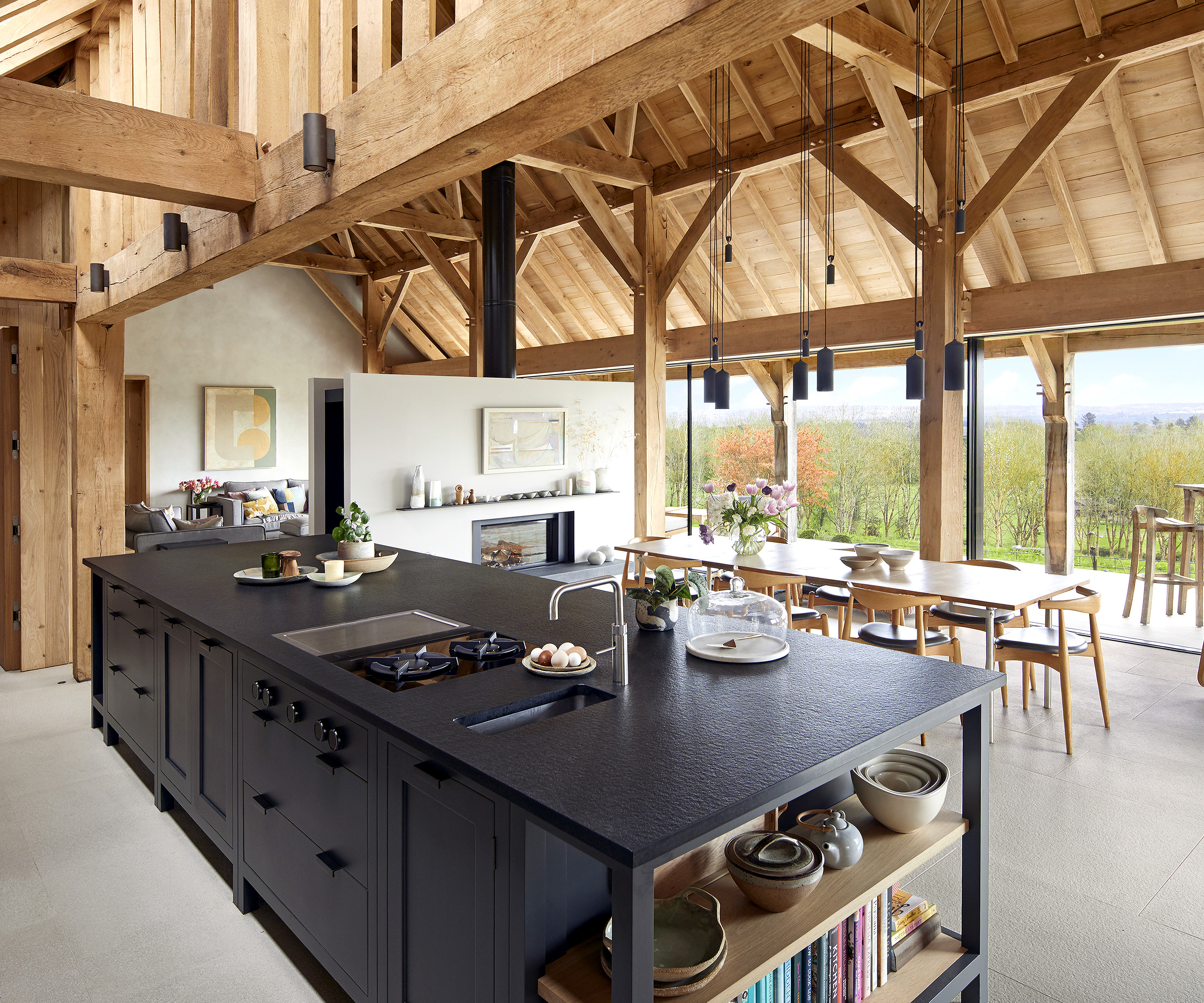 Contemporary open plan living space with timber ceiling beams and frame with large black kitchen island