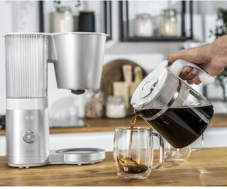 A man pouring coffee from a Zwilling Enfinigy Coffee Maker.