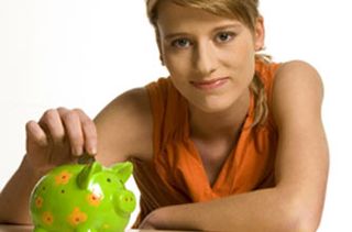 Teenage girl putting money into a piggy bank