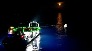 a large boat approaches a white capsule floating in the ocean