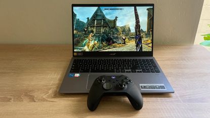 The Steam beta running on a Chromebook. The laptop is atop a wooden desk with a black Xbox controller sat on the front edge.