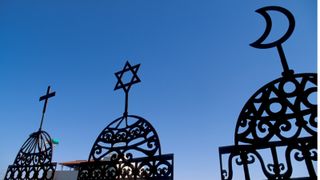 The cross of Christianity, the Star of David from Judaism and the crescent moon of Islam displayed on metal framework