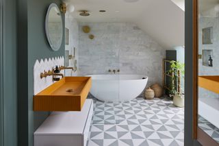 A bathroom with a freestanding white bath, geometric porcelain floor tiles and yellow basin