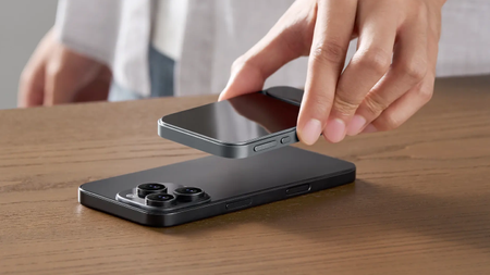 Someone putting the Khadas Tea Pro on top of an iPhone on a wooden surface