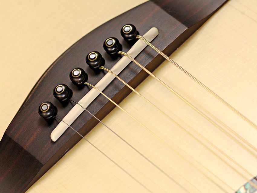 The ebony bridge pins are arranged in a curve to lessen stress along the grain.