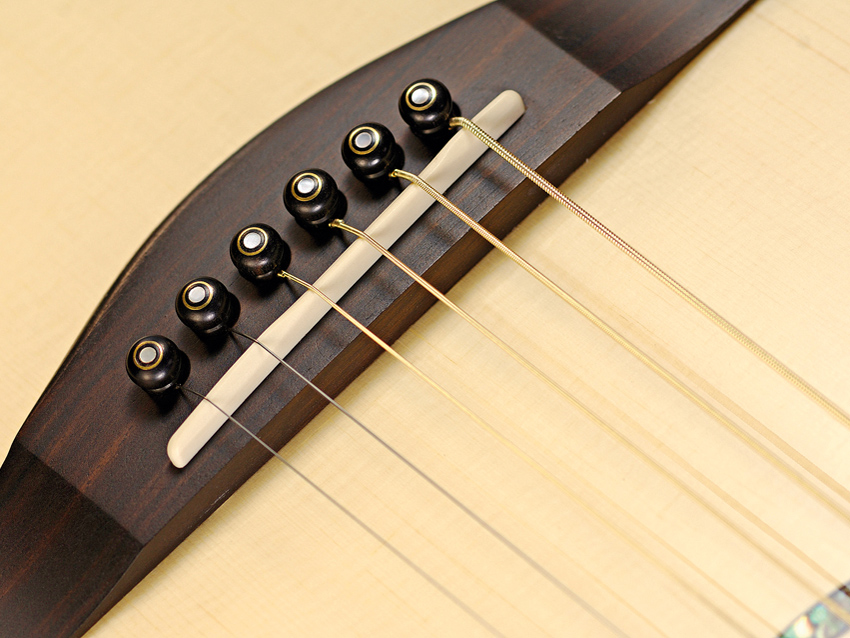 The ebony bridge pins are arranged in a curve to lessen stress along the grain.
