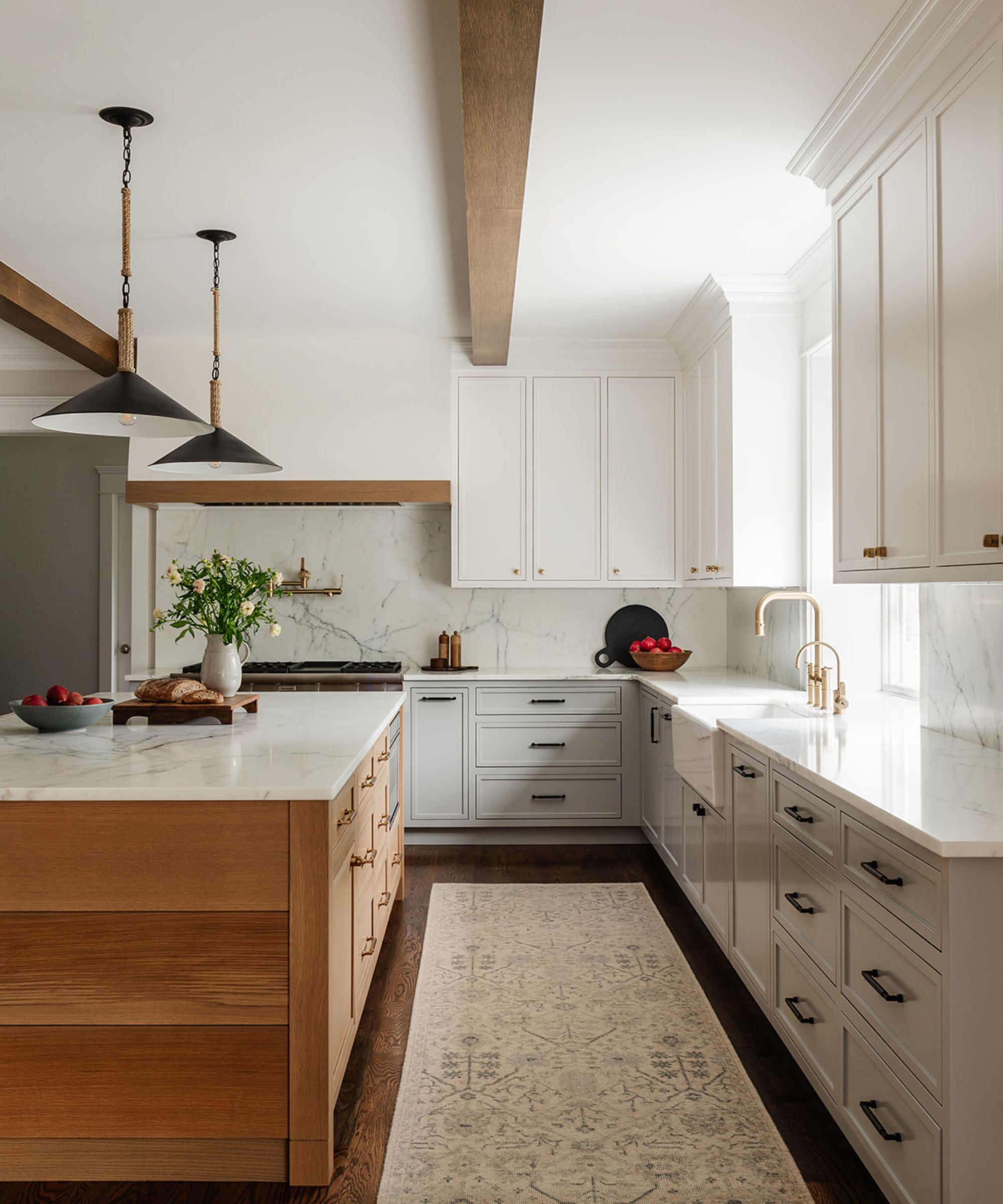 Modern rustic kitchen with beams, cream cabinets, wood and marble island, long rug, and black enamel pendant lights