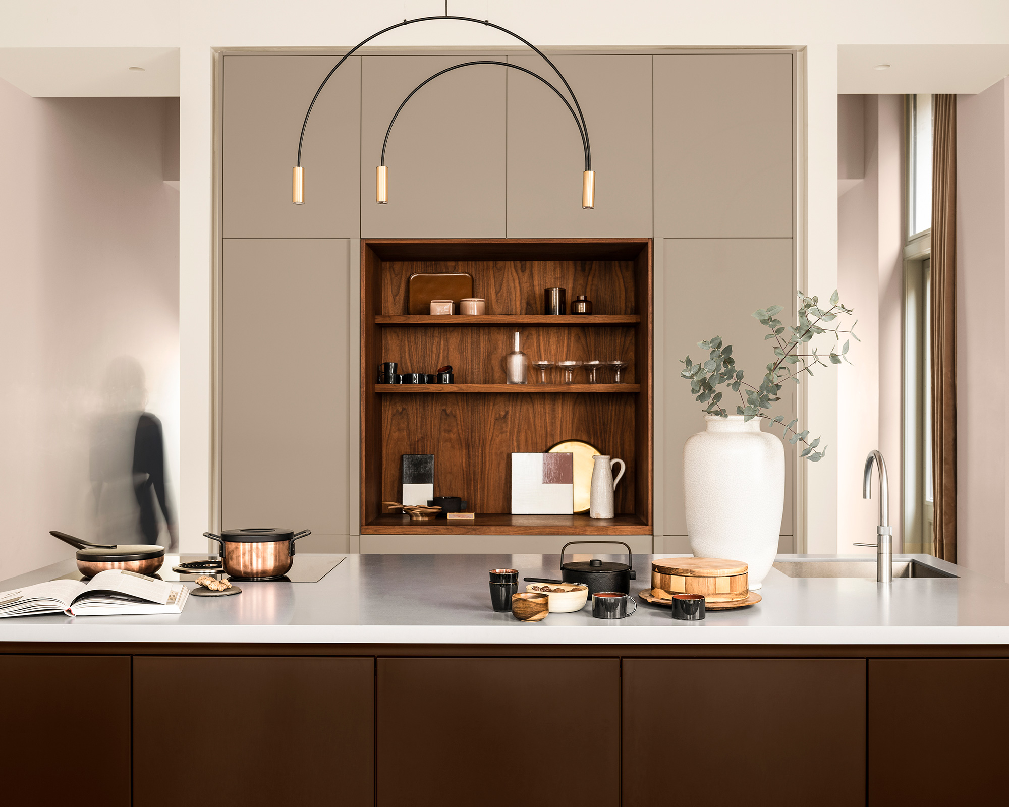 A kitchen with brown and greige cabinetry and wooden shelving