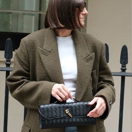 Woman wears tweed jacket, white T-shirt and carries black Bottega Veneta bag