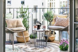 boho style balcony with chairs, rug, cushions, side table, baskets with plants in