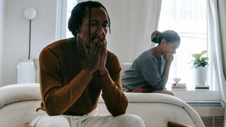Unhappy black couple sitting on bed after having argument