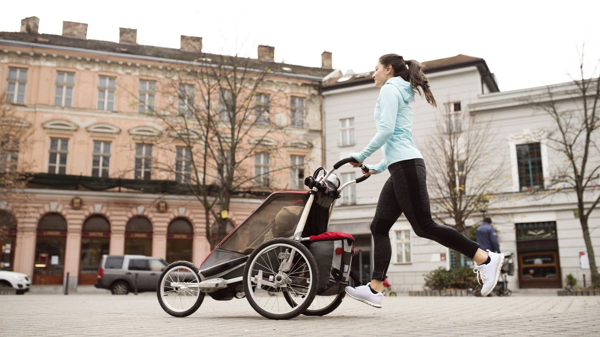 Mother running with child in stroller in the city