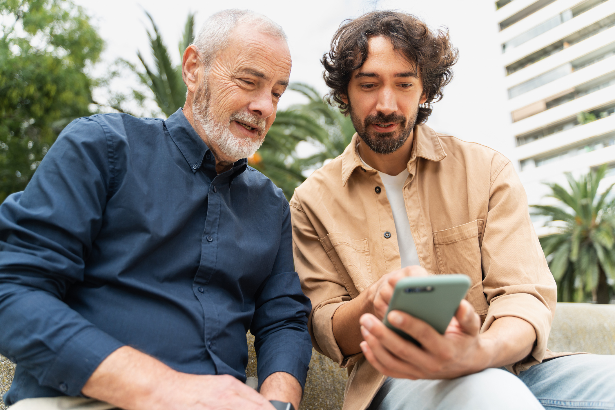 Father and adult son look at a phone.