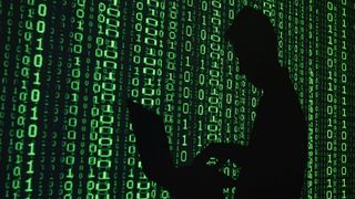 A representational image of a cybercriminal hacking against a Matrix background.