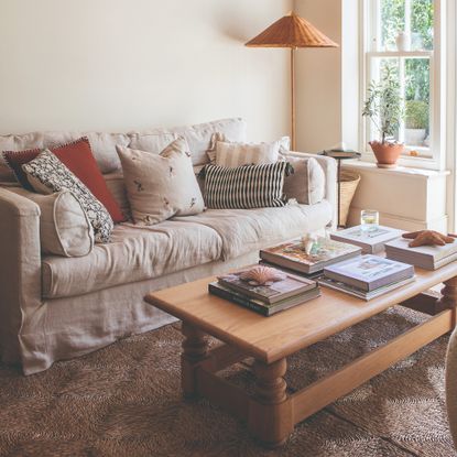 A bright living room with a cream loose cover sofa with mismatched scatter cushions