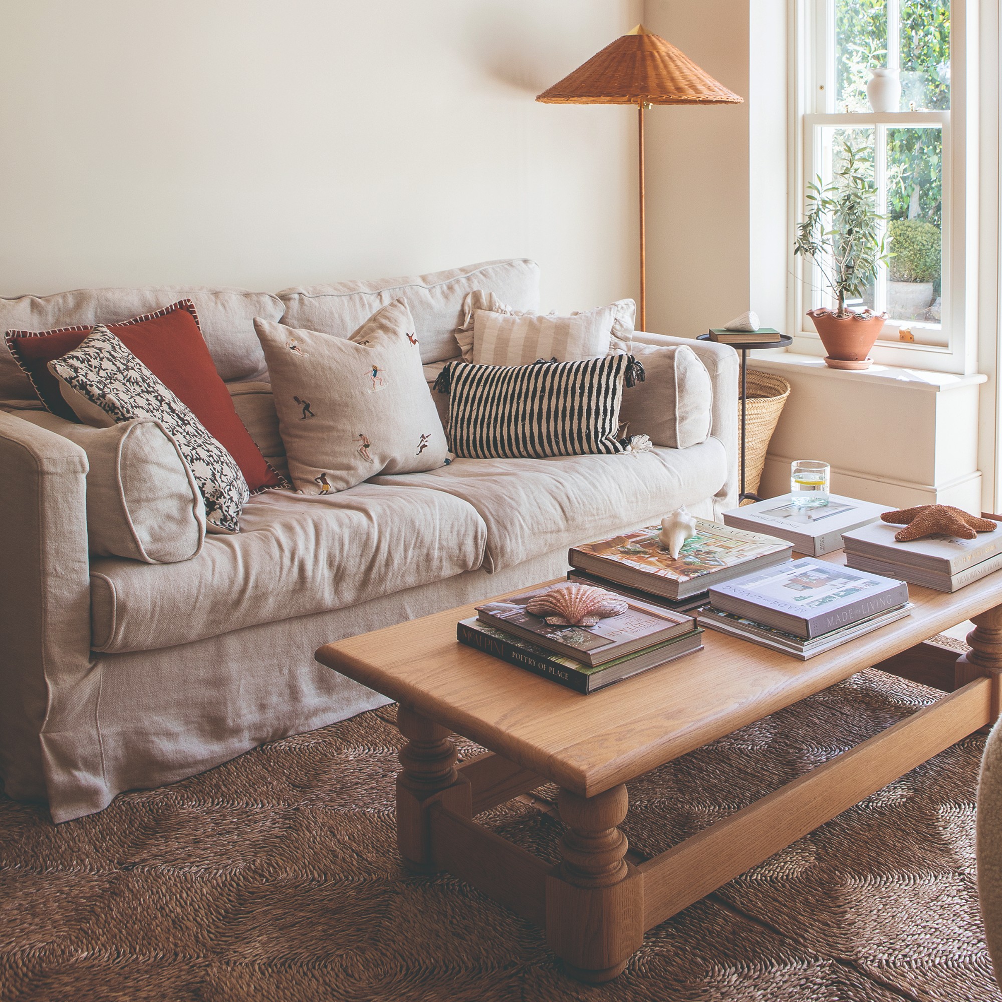 A bright living room with a cream loose cover sofa with mismatched scatter cushions