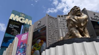 The MGM logo on a large sign in the background, near the MGM Grand Hotel in Las Vegas. In the foreground sits a lion statue, the symbol of MGM.