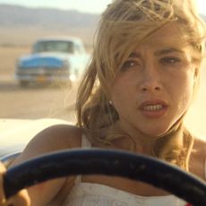 florence pugh as alice driving a car in a car chase in a still from the movie don't worry darling