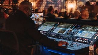 An sound engineer mixes a show on a huge sound board.