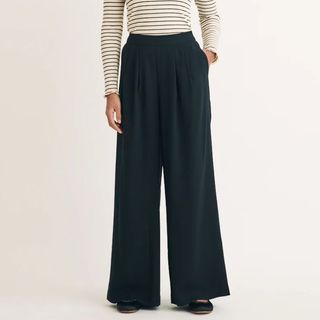 A close up of the bottom half of a model wearing Nobody's Child wide leg black pull on trousers