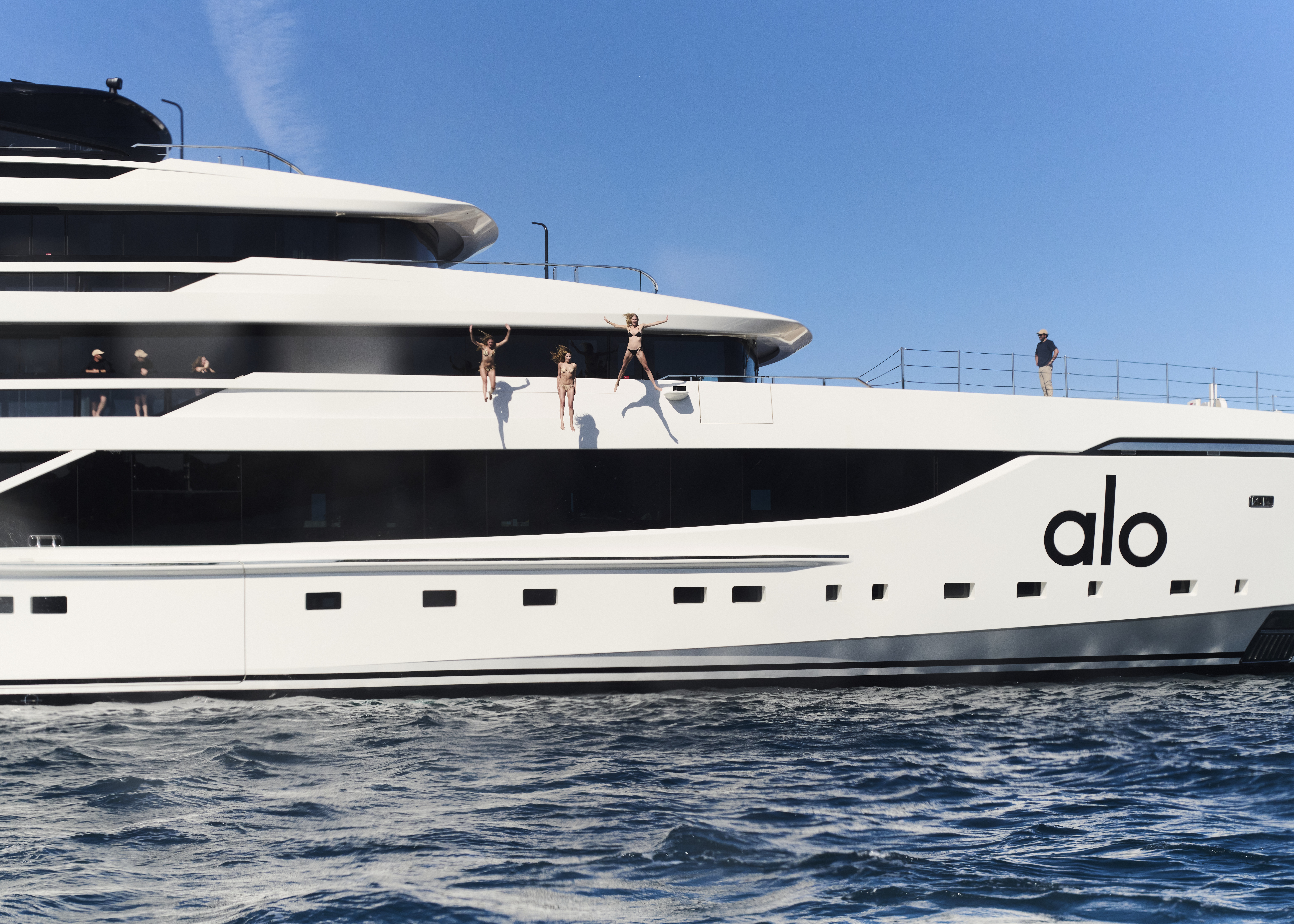 A photo of Eliza Huber and other guests on the Alo yacht jumping off the side of the boat.