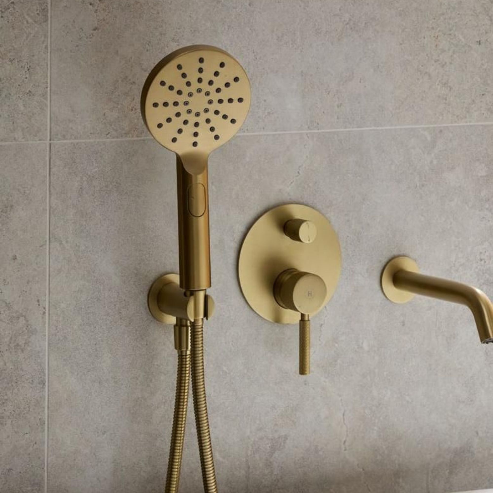 Grey large wall tiles in bathroom with gold shower fittings on wall