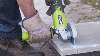 a ryobi angle grinder cutting a concrete tile