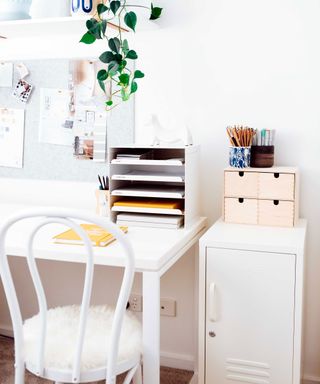 Close up of white desk area in bedroom, white metal storage locker beside desk area, white desk chair with fur seat cushion, desk and locker decorated with small storage trays and pots, high shelf decorated with books and plants