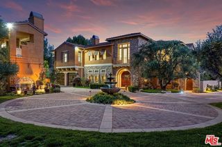 The exterior of a property at dusk with a fountain in the front yard