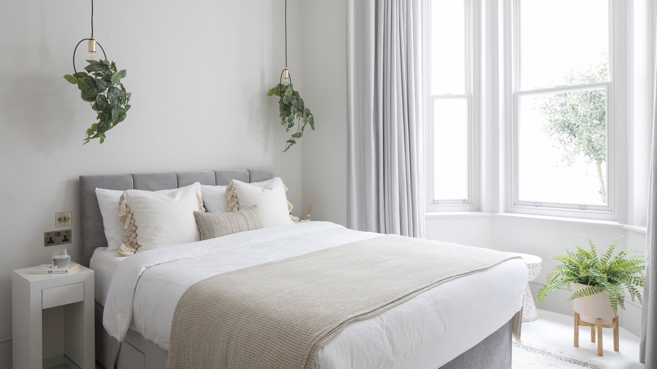 calm bedroom with grey walls and white bed linen plus houseplants