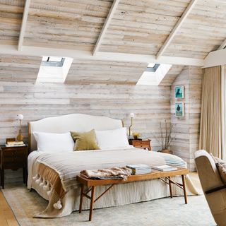 Bedroom with high vaulted ceilings and wood paneling, large bed, matching curtains and armchair