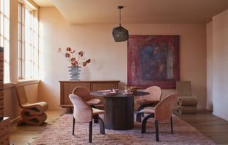 A dining room color drenched in a peach tone with pink and red furniture