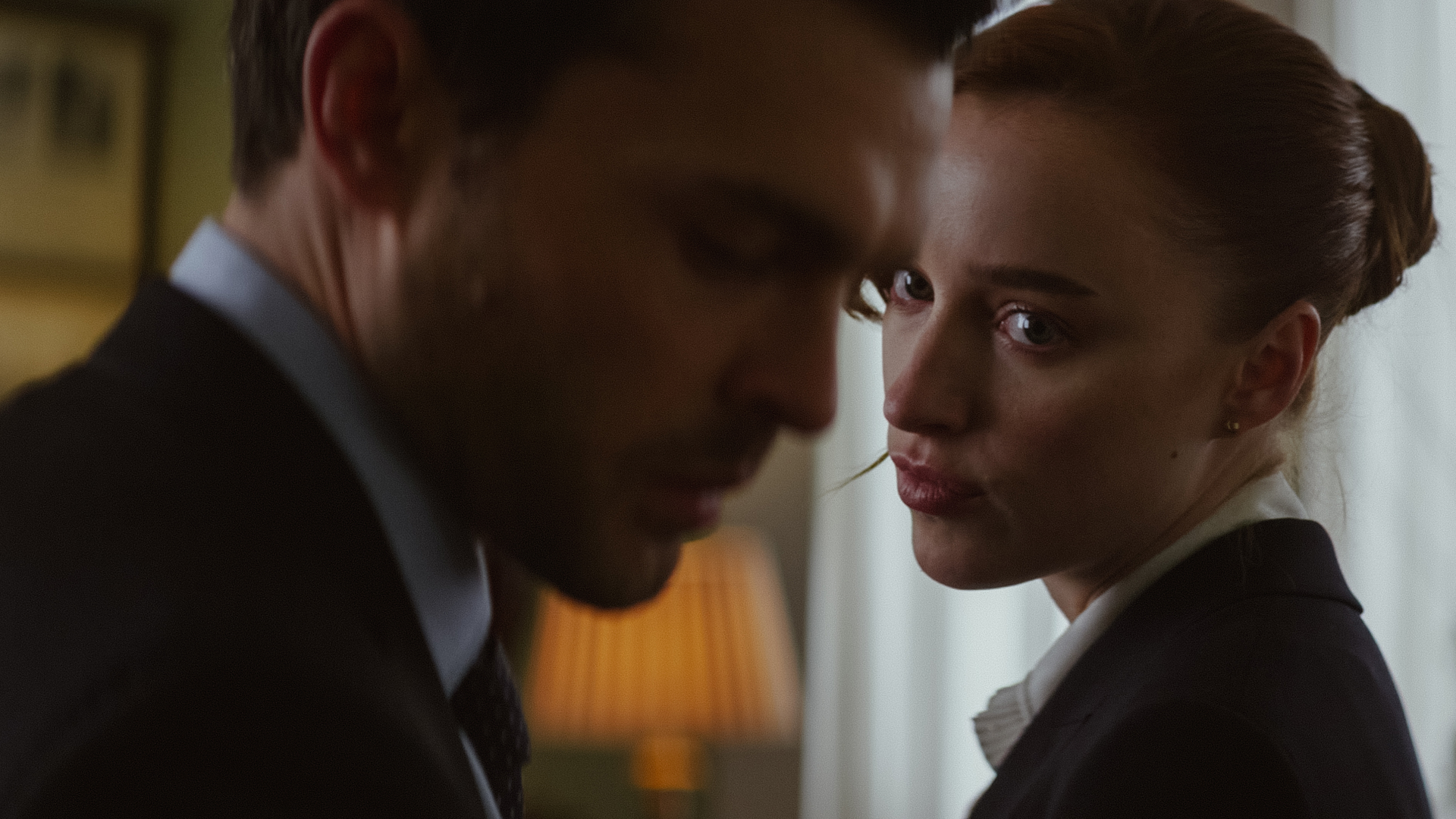 phoebe dynevor looks over her shoulder at alden Ehrenreich in a still from the movie fair play