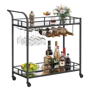 A black metal bar cart with flowers, glasses, bottles, and fruit on it