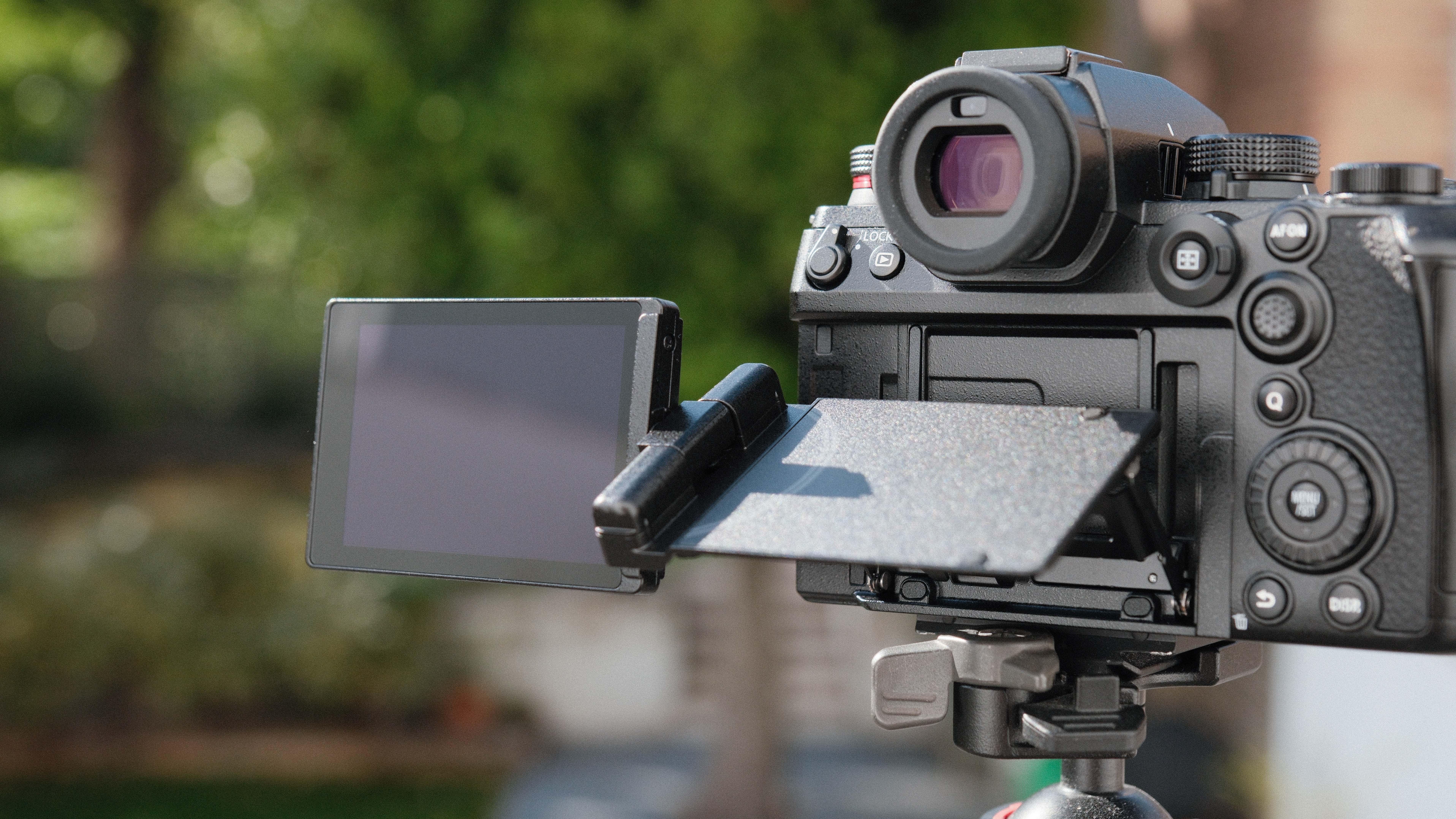 Panasonic Lumix S1 II camera on a tripod with green trees in the background