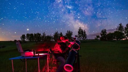 A person looking through a Dobsonian telescope at the stars.