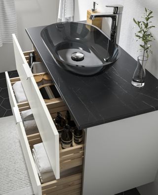 A white bathroom vanity with a glass countertop sink