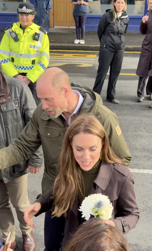 Prince William guiding Princess Kate along a row of fans