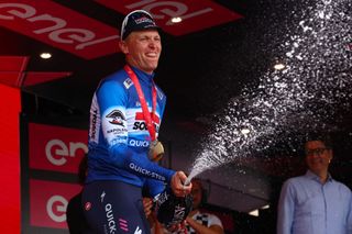 Team Soudal-Quick Step's Belgian rider Tim Merlier sprays champagne on the podium after winning the 18th stage of the 107th Giro d'Italia cycling race, 178km between Fiera di Primiero and Padua on May 23, 2024. (Photo by Luca Bettini / AFP)