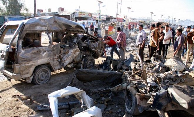 Residents gather at the site of a car bomb attack on April 25 in Baghdad that killed at least eight and wounded 23 others.