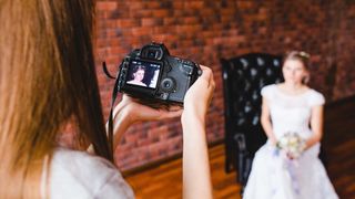 Female wedding photographer reviewing image of the bride